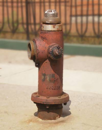 A thin, partly-rusted, red hydrant with a silver bonnet is missing a pumper nozzle cap.